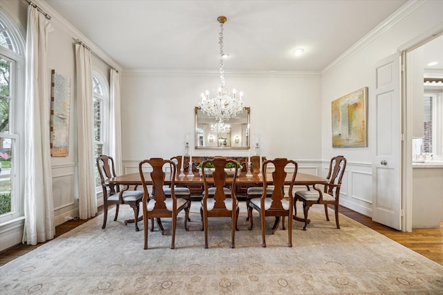 dining area featuring a notable chandelier, light hardwood / wood-style floors, crown molding, and a wealth of natural light