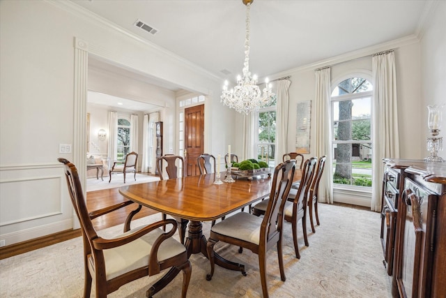 dining room featuring a notable chandelier, ornamental molding, and light wood-type flooring