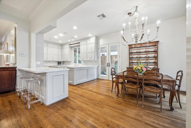 kitchen with a breakfast bar, light stone counters, white cabinetry, light hardwood / wood-style floors, and decorative backsplash