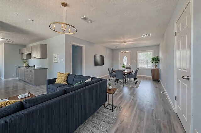 living room with light hardwood / wood-style floors, an inviting chandelier, and a textured ceiling