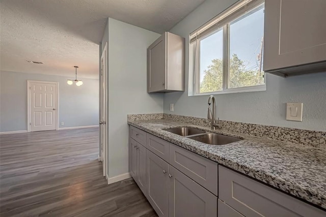 kitchen with dark hardwood / wood-style floors, sink, a textured ceiling, and decorative light fixtures