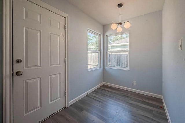 unfurnished dining area featuring a notable chandelier and dark hardwood / wood-style floors