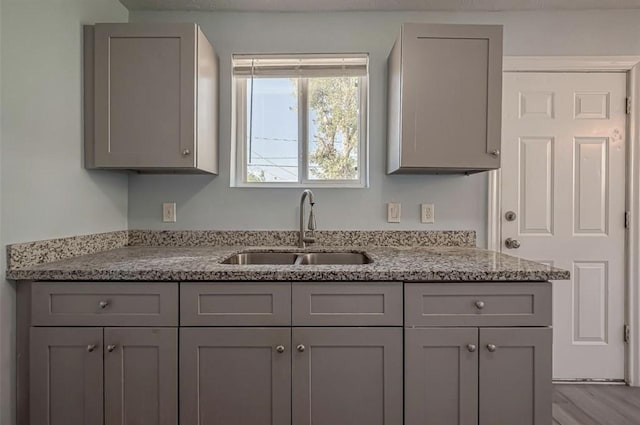 kitchen featuring gray cabinets, sink, and light stone counters