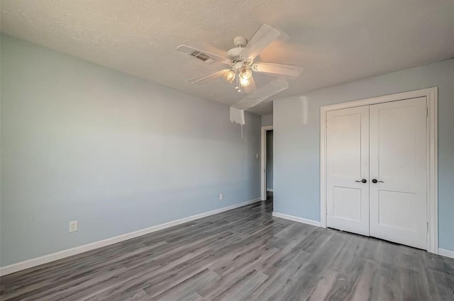 unfurnished bedroom featuring hardwood / wood-style floors, a closet, ceiling fan, and a textured ceiling