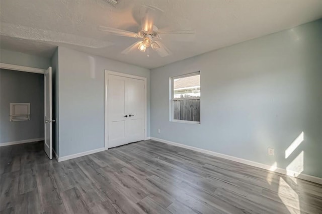 unfurnished bedroom featuring a textured ceiling, a closet, hardwood / wood-style floors, and ceiling fan