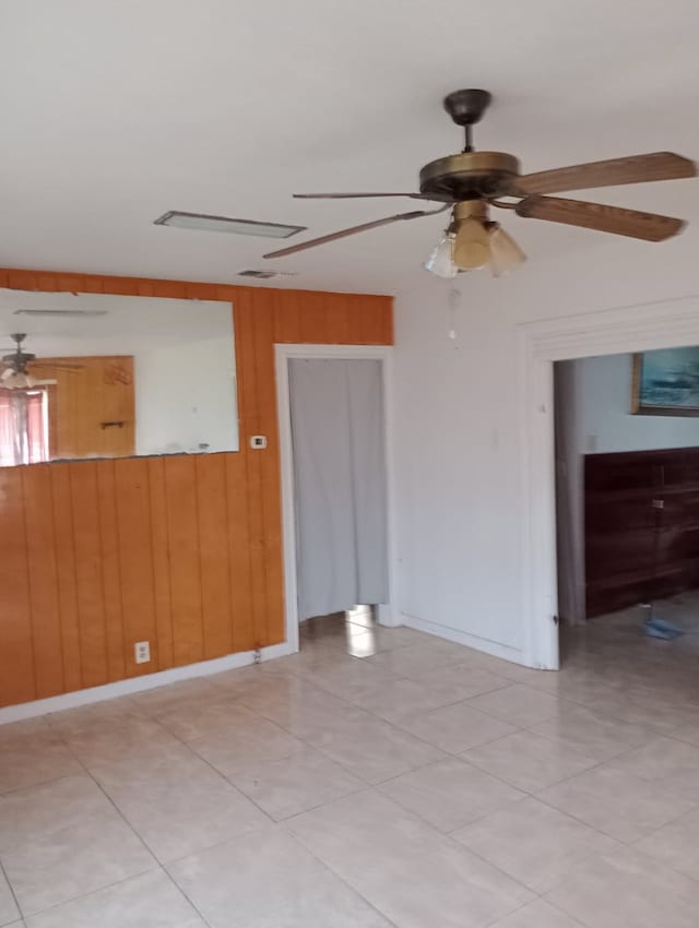 unfurnished room featuring ceiling fan and wooden walls