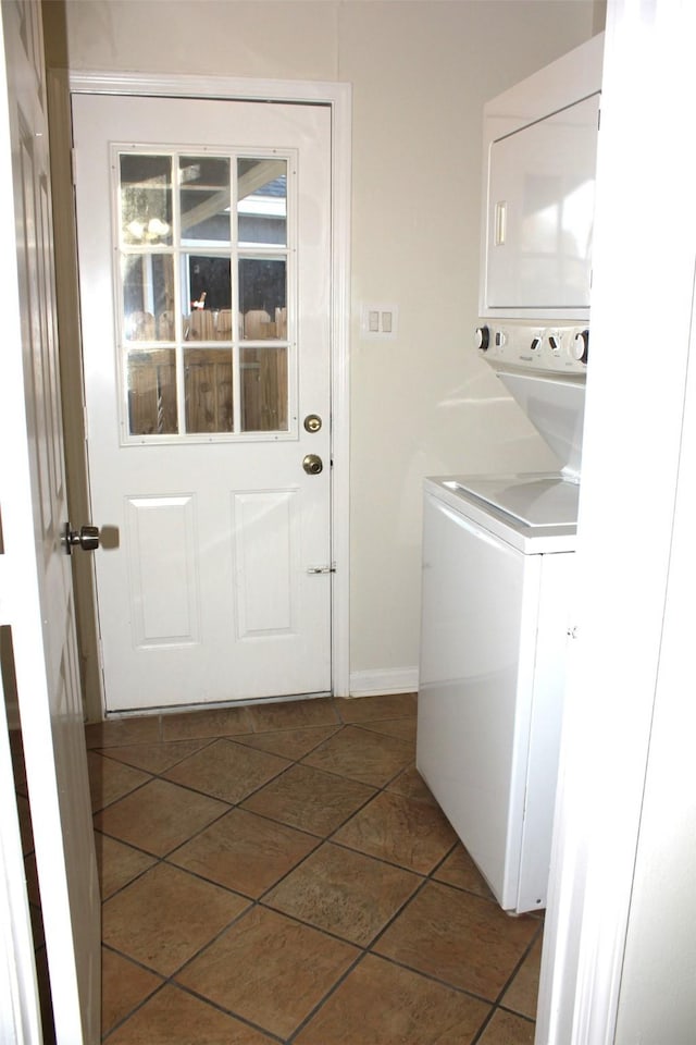 washroom featuring dark tile patterned flooring and stacked washer and clothes dryer