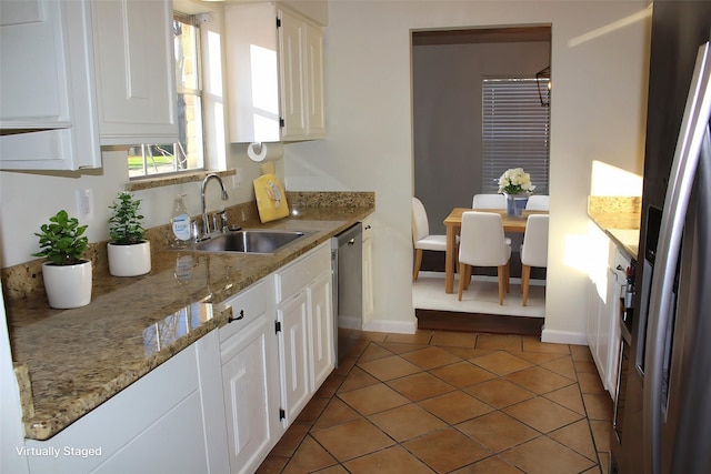 kitchen with appliances with stainless steel finishes, sink, light stone counters, and white cabinets