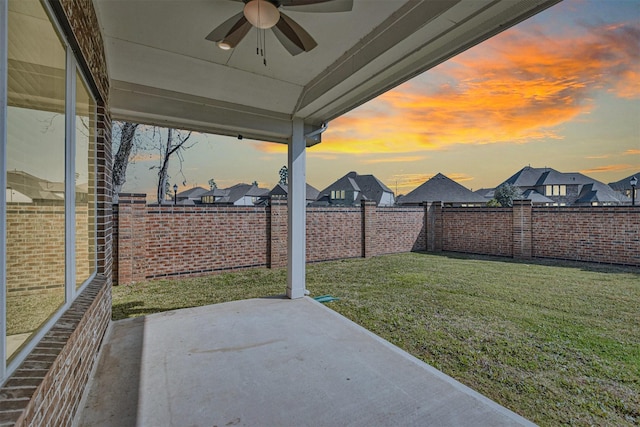 yard at dusk featuring a patio and ceiling fan