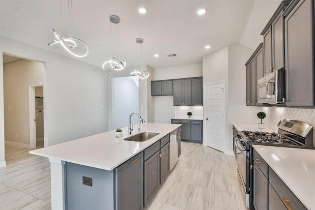 kitchen with a kitchen island with sink, stainless steel appliances, sink, decorative backsplash, and pendant lighting