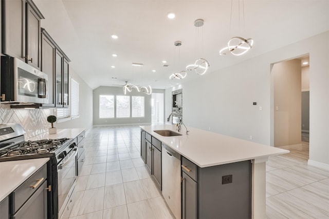 kitchen with sink, pendant lighting, stainless steel appliances, a kitchen island with sink, and decorative backsplash