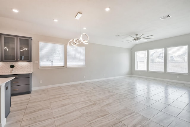 kitchen featuring dark brown cabinets, hanging light fixtures, lofted ceiling, decorative backsplash, and ceiling fan with notable chandelier