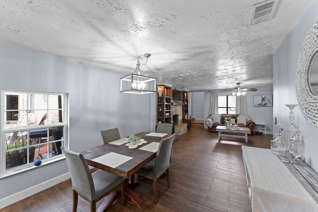 dining space featuring ceiling fan with notable chandelier, dark hardwood / wood-style flooring, and a textured ceiling