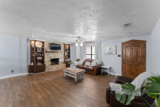 living room with a textured ceiling, a stone fireplace, ceiling fan, and dark hardwood / wood-style flooring