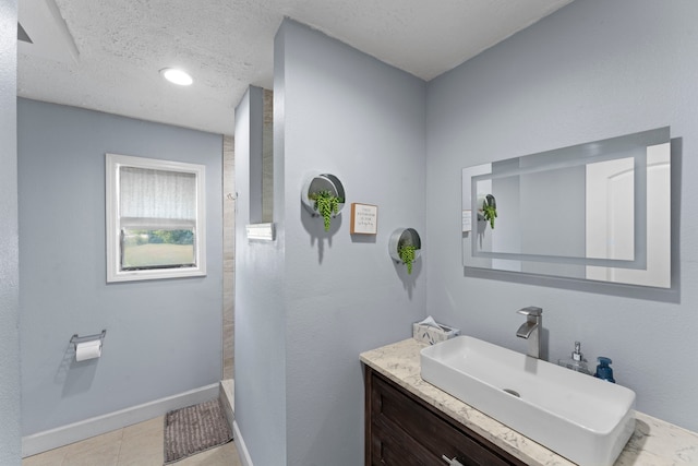 bathroom with a textured ceiling, vanity, and walk in shower