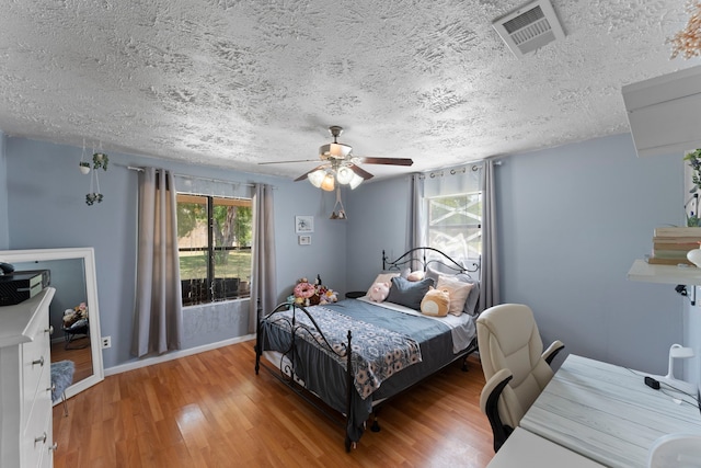 bedroom featuring hardwood / wood-style flooring, ceiling fan, and a textured ceiling