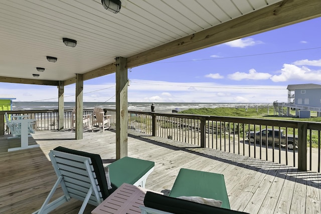 wooden deck featuring a water view and a view of the beach