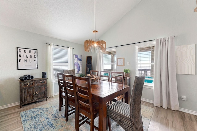 dining room with a textured ceiling, lofted ceiling, and light hardwood / wood-style flooring