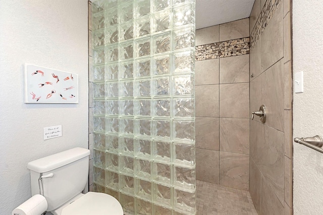 bathroom featuring a tile shower and toilet