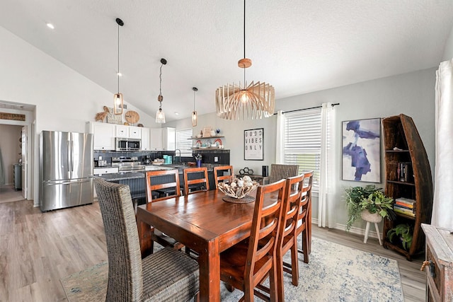 dining area featuring light hardwood / wood-style flooring, sink, a textured ceiling, and lofted ceiling