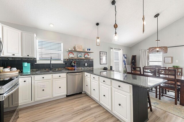 kitchen with white cabinetry, kitchen peninsula, hanging light fixtures, sink, and appliances with stainless steel finishes