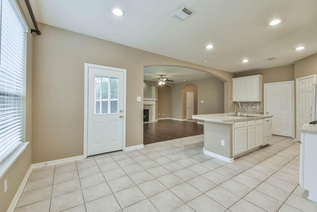 kitchen with white cabinets, light tile patterned flooring, backsplash, sink, and a kitchen island with sink