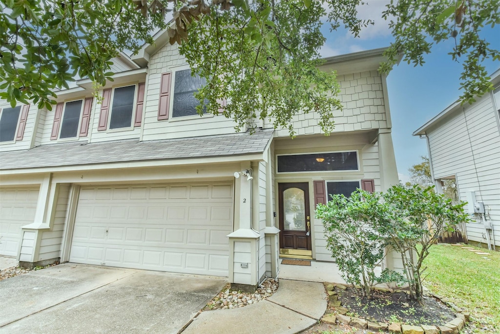 townhome / multi-family property featuring a garage, driveway, and a shingled roof