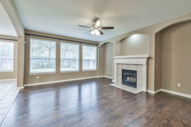 unfurnished living room featuring hardwood / wood-style floors, ceiling fan, and a fireplace