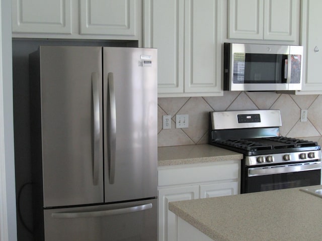 kitchen with white cabinets, appliances with stainless steel finishes, and decorative backsplash