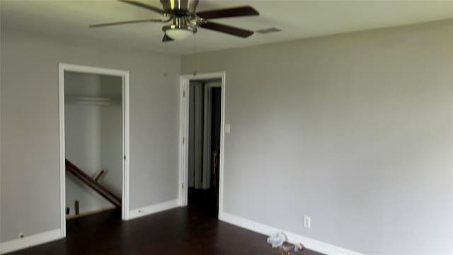 unfurnished bedroom featuring visible vents, a ceiling fan, dark wood finished floors, baseboards, and a closet