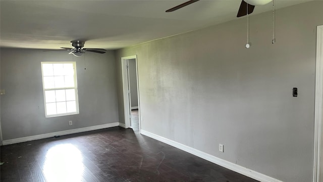 empty room featuring baseboards, a ceiling fan, and dark wood-type flooring