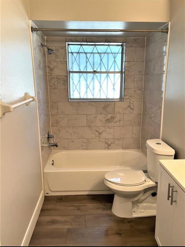 bathroom featuring toilet, washtub / shower combination, vanity, wood finished floors, and baseboards