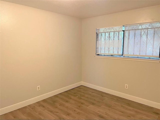 spare room with wood finished floors and baseboards