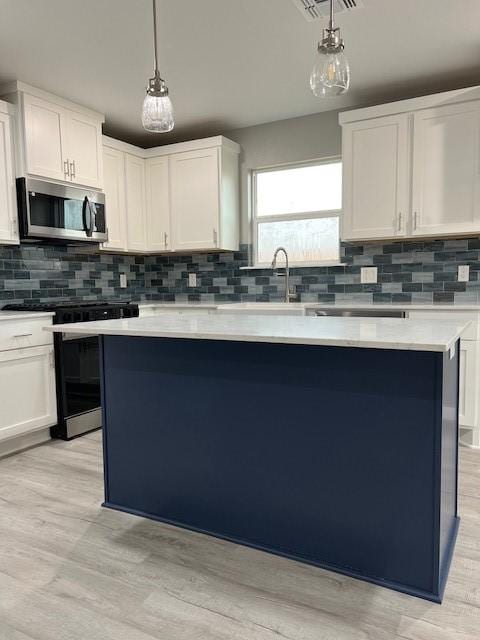 kitchen with pendant lighting, white cabinetry, a center island, and gas stove