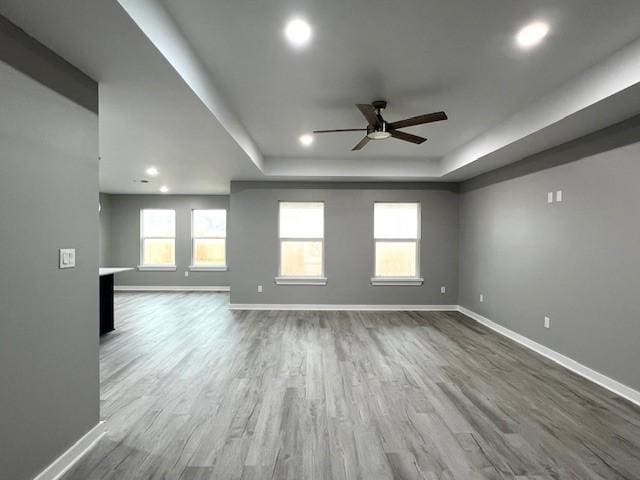 unfurnished room with a tray ceiling, ceiling fan, and hardwood / wood-style floors