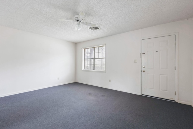 empty room featuring dark carpet, ceiling fan, and a textured ceiling