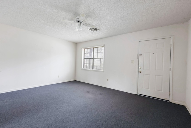 unfurnished room with a textured ceiling, dark colored carpet, and ceiling fan