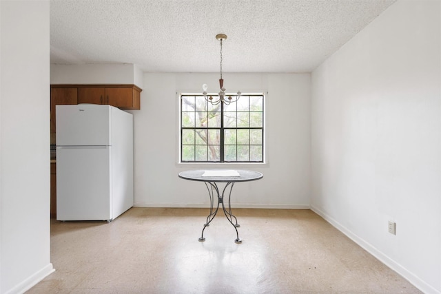 unfurnished dining area featuring a textured ceiling and an inviting chandelier