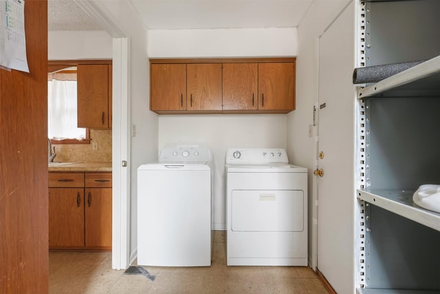 clothes washing area featuring cabinets, sink, and washing machine and clothes dryer