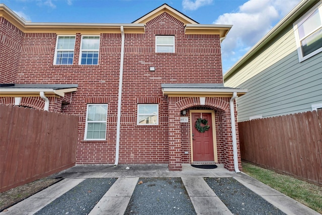 view of front of house featuring brick siding and fence