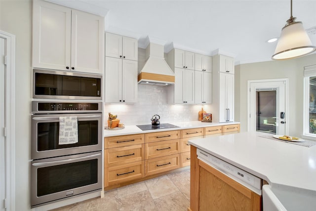 kitchen featuring pendant lighting, light countertops, white cabinets, custom exhaust hood, and black electric stovetop