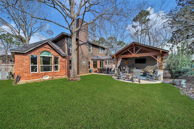 rear view of property with brick siding, a chimney, a patio, a gazebo, and a yard