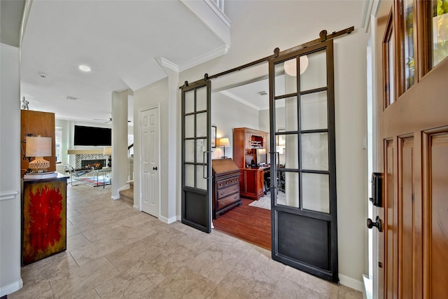 hallway with baseboards, stairs, a barn door, and ornamental molding