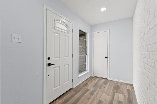 doorway to outside featuring hardwood / wood-style floors and brick wall