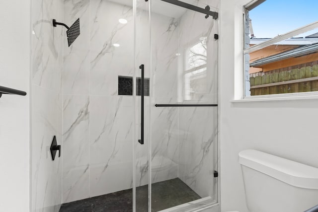 bathroom with a shower with shower door and toilet