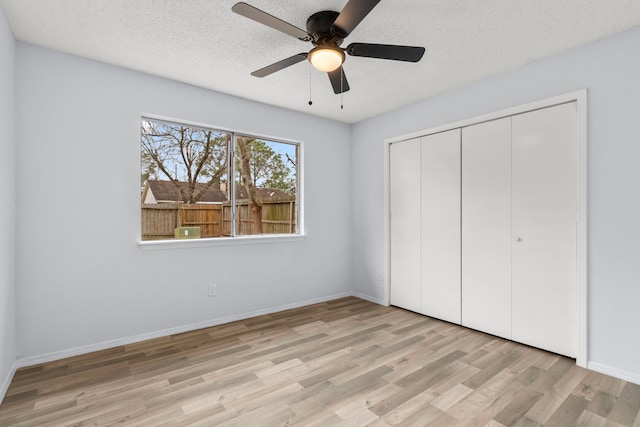 unfurnished bedroom featuring light hardwood / wood-style flooring, ceiling fan, a closet, and a textured ceiling