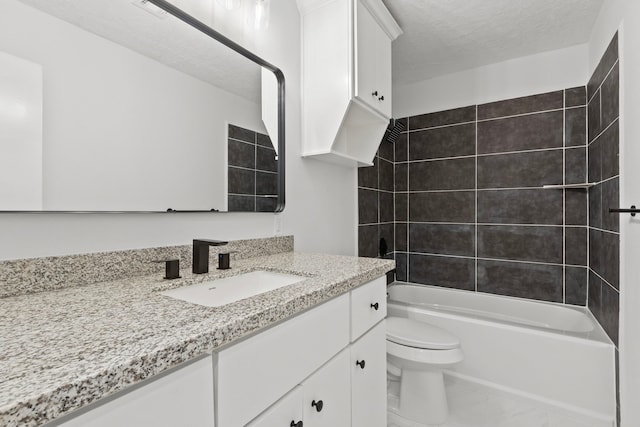 full bathroom featuring toilet, vanity, a textured ceiling, and tiled shower / bath