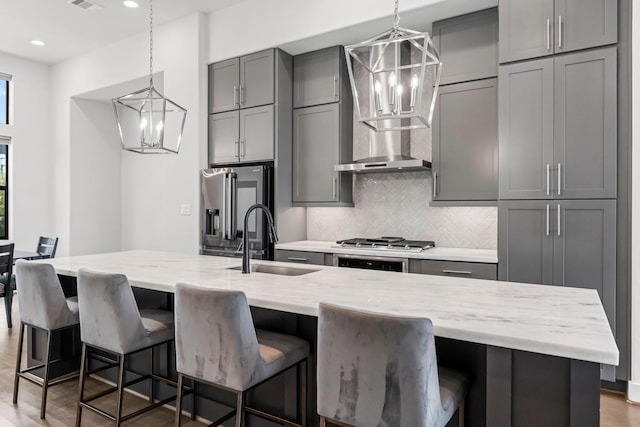 kitchen featuring gray cabinetry, sink, a breakfast bar area, and light stone countertops