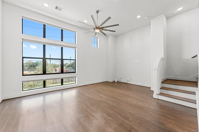 unfurnished living room with ceiling fan, dark wood-type flooring, and a high ceiling