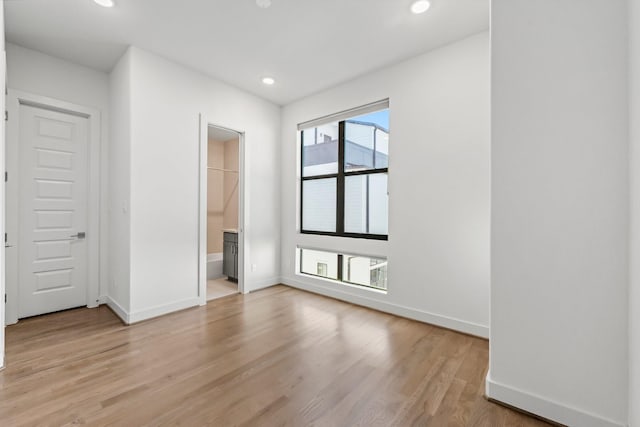 unfurnished bedroom with light wood-type flooring and ensuite bath